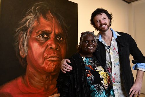 Aboriginal Elder Daisy Tjuparntarri Ward and artist David Darcy pose for a photograph in front of David's portrait of Daisy.