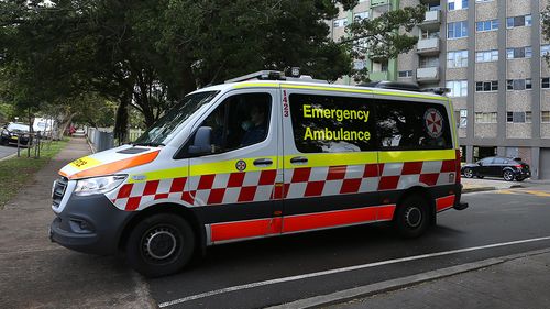 An ambulance is seen departing a housing tower on Morehead Street in Redfern. Health authorities are working to contain an emerging COVID-19 cluster across three social housing towers in the inner-city suburb.