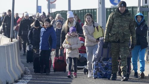 A Polish border guard assists refugees from Ukraine as they arrive to Poland at the Korczowa border crossing, Poland.