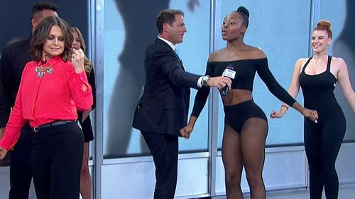 Lisa gives J-Lo's moves a try while Karl is preoccupied holding a mic for demo dancer Ebony. (9NEWS)
