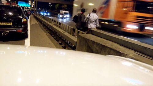 Couple run across six-lane motorway to escape traffic jam