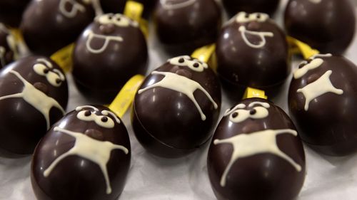 A tray of chocolate Easter eggs with face masks are laid out on a tray at the Chocolate Line warehouse of Dominique Persoone in Bruges, Belgium, Friday, April 10, 2020