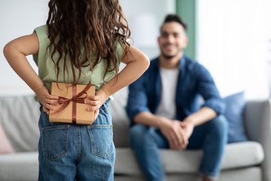 Little girl greeting her arabic dad with Fathers Day, holding gift behing back. Female child making surpsise to daddy at home, hiding present box, congratulating with holiday, selective focus