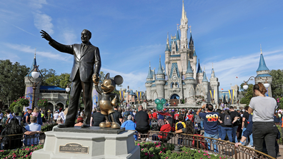 FILE - In this Jan. 9, 2019 photo, guests watch a show near a statue of Walt Disney and Micky Mouse in front of the Cinderella Castle at the Magic Kingdom at Walt Disney World in Lake Buena Vista, part of the Orlando area in Fla.  (AP Photo/John Raoux, File)