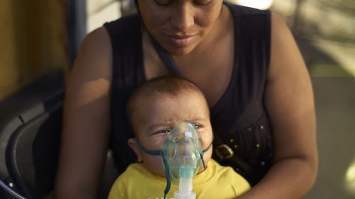 Honduran migrant Janet Zuniga holds her five-month-old son Linder, as he receives medical treatment outside a shelter, November 36 in Tijuana, Mexico.