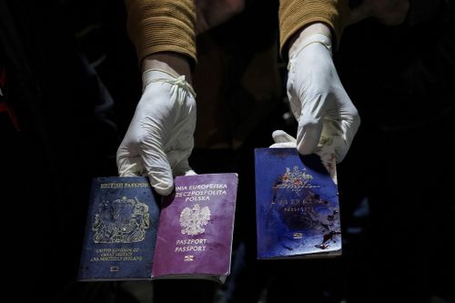 A man displays blood-stained British, Polish, and Australian passports after an Israeli airstrike, in Deir al-Balah, Gaza Strip, Monday, April 1, 2024. 