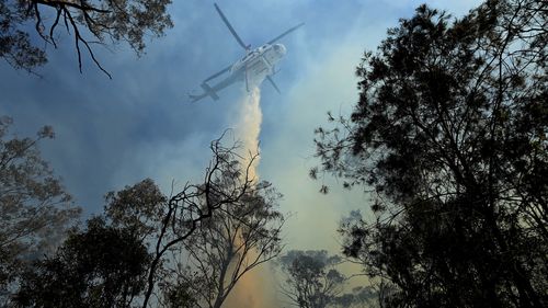 A helicopter dumps water on a bushfire on Silverdale Road in Wallacia