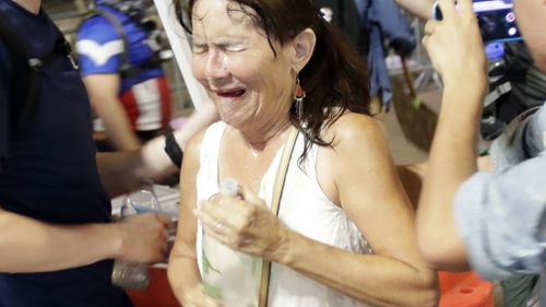 A protestor attempts to clean out her eyes after police release tear gas. (AAP)