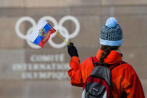  A woman holds a Russian flag in front of the Olympic Rings logo during the Executive Board meeting, at the International Olympic Committee (IOC) headquarters, in Pully near Lausanne, Switzerland. (AAP)