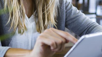 Young woman using her digital tablet while drinking coffee in the coffee shop