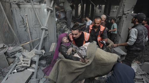 Palestinian rescuers evacuate an injured woman that was found under the rubble of a destroyed house 