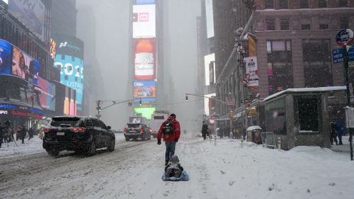 David Suker pulls his son Tadhg Suker during heavy snowfall in New York's Times Square. (AAP)