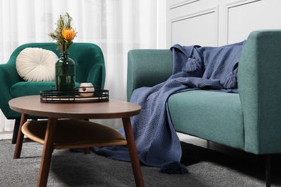 Comfortable sofa, blanket, table and armchair in living room