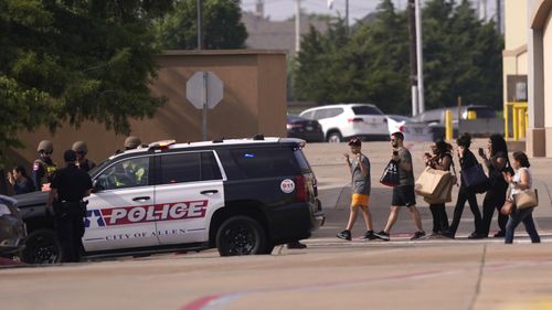 2023 年 5 月 6 日，星期六，德克萨斯州艾伦，枪击事件发生后，人们在离开购物中心时举手。