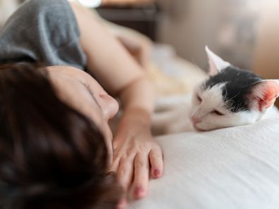 Relaxed cat and teenage girl on bed at home