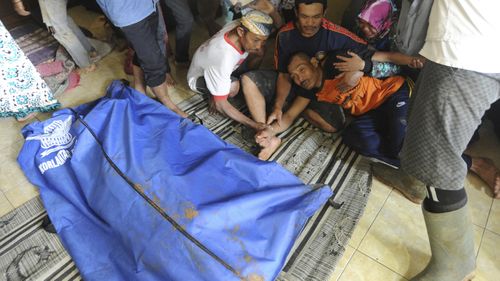 A man reacts near a body bag containing the body of his relative who was killed by the landslide.