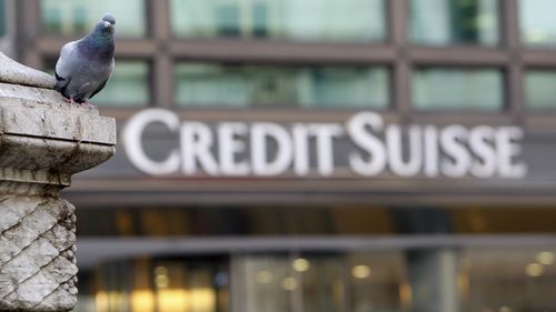 FILE - A pigeon rests near a building hosting offices of Credit Suisse bank in Milan, Tuesday, Oct. 27, 2009. 