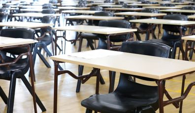 View of large exam room hall and examination desks tables lined up in rows ready for students at a high school to come and sit their exams tests papers.