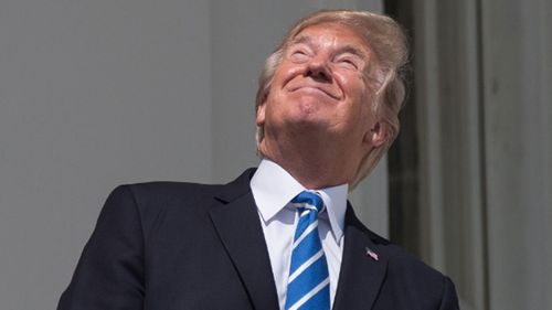 Mr Trump briefly defied warnings not to look at the sun without protective glasses. (AAP)