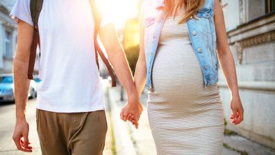Man walking hand in hand with pregnant partner