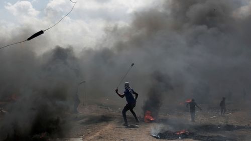 Palestinian protesters hurl stones at Israeli troops during a protest on the Gaza Strip's border with Israel