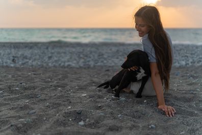 Woman with a dog on the beach, pet-friendly holiday