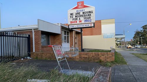 A shopping trolley and a sign that reads 'we are moving to Moorebank, back in 2023' sits in front of the old fire station.
