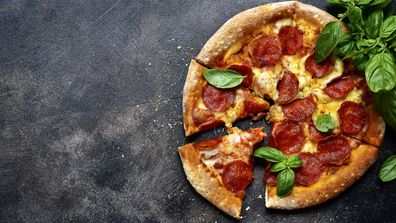 Traditional italian pizza pepperoni with salami and cheese on a dark slate, stone, metal or concrete background.Top view with copy space.