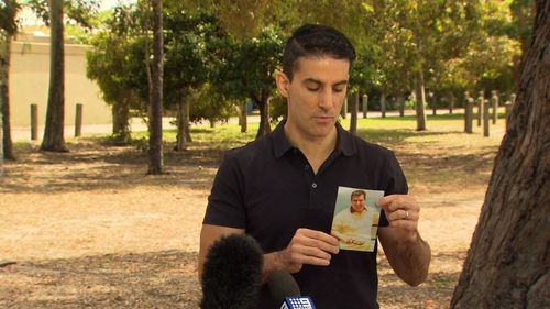 Mr Saristavros' son holds a picture of his murdered father during a press conference this morning.