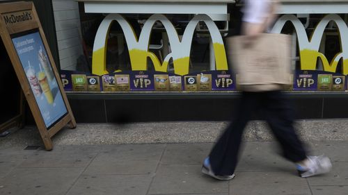 A woman walks by a McDonald's restaurant, in London, Tuesday, Aug. 24, 2021. McDonalds says it has pulled milkshakes from the menu in all 1,250 of its British restaurants because of supply problems stemming from a shortage of truck drivers. The fast-food chain says it is also experiencing shortages of bottled drinks. (AP Photo/Alastair Grant)