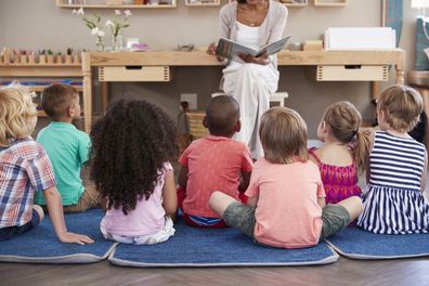 Kindergarten class listening to a story. Kindergarten teacher.