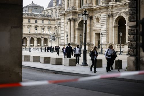 Staff leave the Louvre Museum as people are evacuated after it received a written threat, in Paris, Saturday Oct. 14, 2023.  