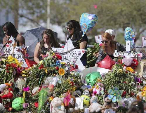 Mourners bring flowers as they pay tribute at a memorial for the victims of the shooting. (AAP)