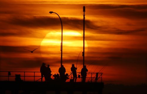 Fisherman take in a beautiful sunrise over Melbourne this morning before things heated up.