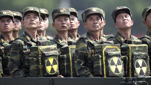 North Korean soldiers bear parcels marked with the nuclear symbol at a parade.