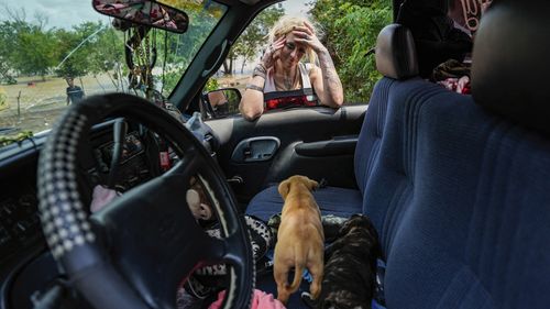 A woman, identified only as Lisamarie, checks on two of her puppies after her neighborhood was evacuated due to severe flooding Saturday, May 4, 2024, in Channelview, Texas.  (Raquel Natalicchio/Houston Chronicle via AP)