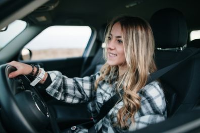 A teenager girl sitting in the driver seat of a car