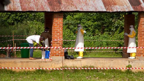 Health workers are sprayed with chlorine after leaving the isolation ward to diagnose and treat suspected Ebola patients. Picture: AP