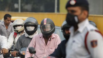 Motorcyclists cover their faces with scarf to save themselves from air pollution as they wait at a crossing in New Delhi, India.
