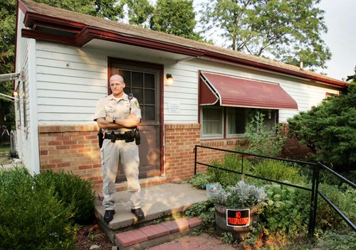 A Kansas police officer guards the front door of Dennis Rader's home in Park City. Rader, who pleaded guilty last month to killing 10 people in the Wichita area from 1974 to 1991, called himself BTK, for "Bind, Torture, Kill," in messages to media and police about the crimes. The house was auctioned off for US $90,000 in 2005.