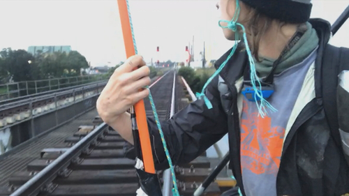 A climate change protester has suspended himself from a rail bridge in Sydney.