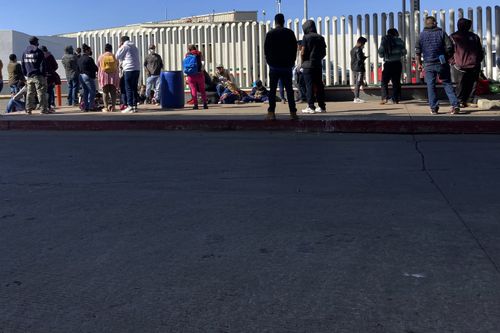 Migrants waiting to cross into the United States wait for news at the border crossing Wednesday, February 17, 2021, in Tijuana.