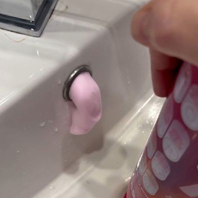 Yugou foam drain cleaner from The Reject Shop being used on a bathroom sink drain as foam emerges from the overflow hole