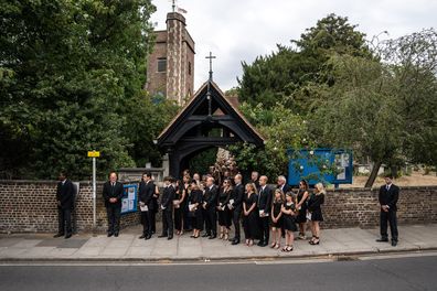 Friends and family look on as the cortege for Dame Deborah James leaves following her funeral at St Mary's Church on July 20, 2022 in Barnes, England.  