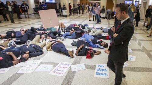 A Florida Rep. surveys a group of 20 students and activists as they stage a die-in on the 4th floor rotunda between the House and Senate chambers. Inside, the House took up the school safety bill. (AAP/AP)