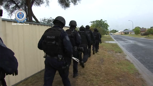 Tactical police prepare to execute a search warrant shortly after 7am yesterday.