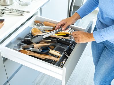 Woman getting something out of a cluttered kitchen drawer