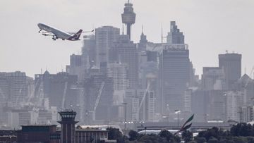 Qantas commercial aircraft taking off across Sydney&#x27;s skyline photographed From Dolls Point on Botany Bay