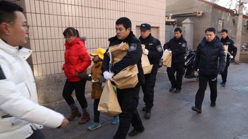 Crime scene investigators as they carry evidence bags.