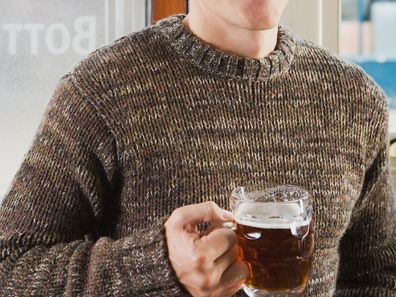 Man wearing jumper drinking beer in pub